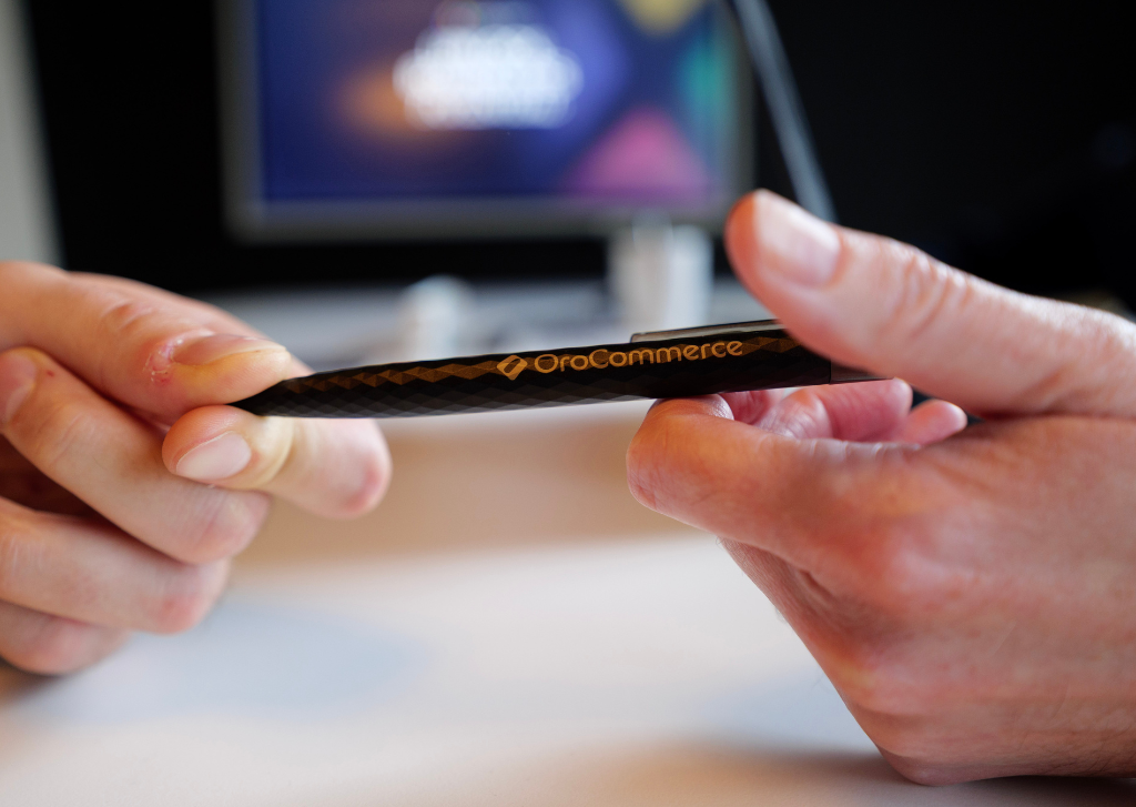 2 personen geven een pen van OroCommerce door